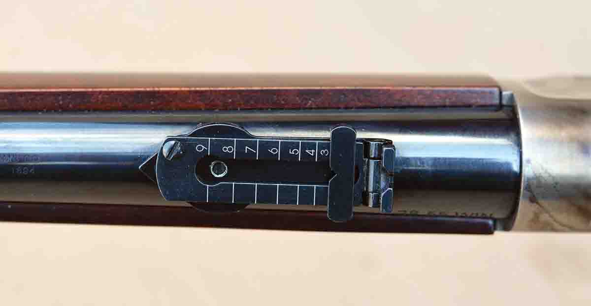 The ladder rear sight features graduation markings from 2 through 9.